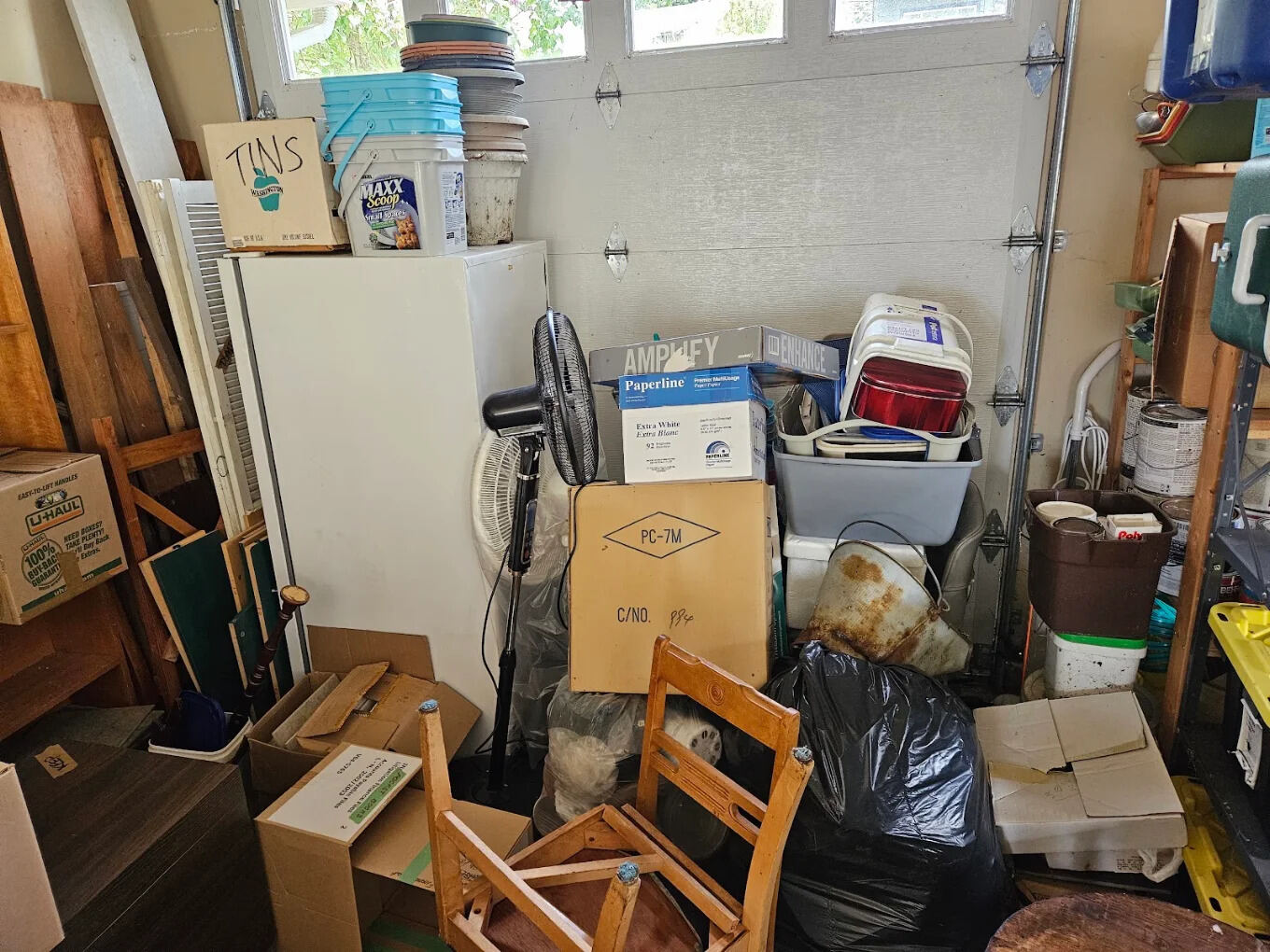Cluttered garage full of boxes and old furniture before a cleanout